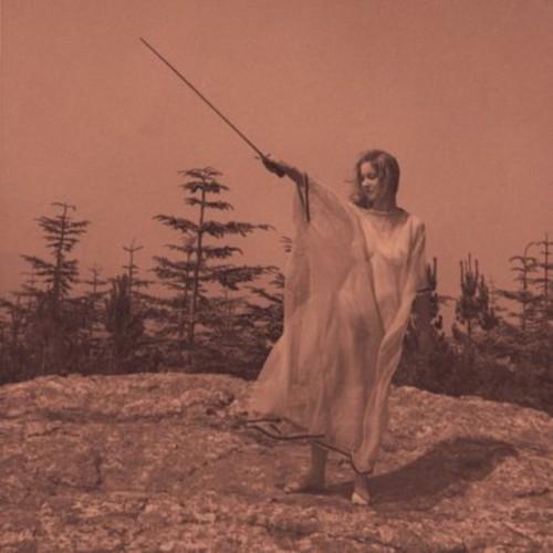 Person in a long robe holding a staff in a forest setting with a pinkish hue.