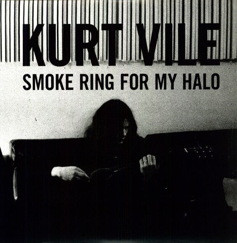 The image features Kurt Vile, the artist behind the album 'Smoke Ring For My Halo'. He is seated, playing an instrument, with a dark backdrop that has the title 'KURT VILE SMOKE RING FOR MY HALO' printed at the top.