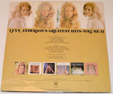 Vinyl record back cover for Lynn Anderson's Greatest Hits Volume II showing four headshots of her at the top, six of her album covers at the bottoma and black text listing the song titles in the middle.